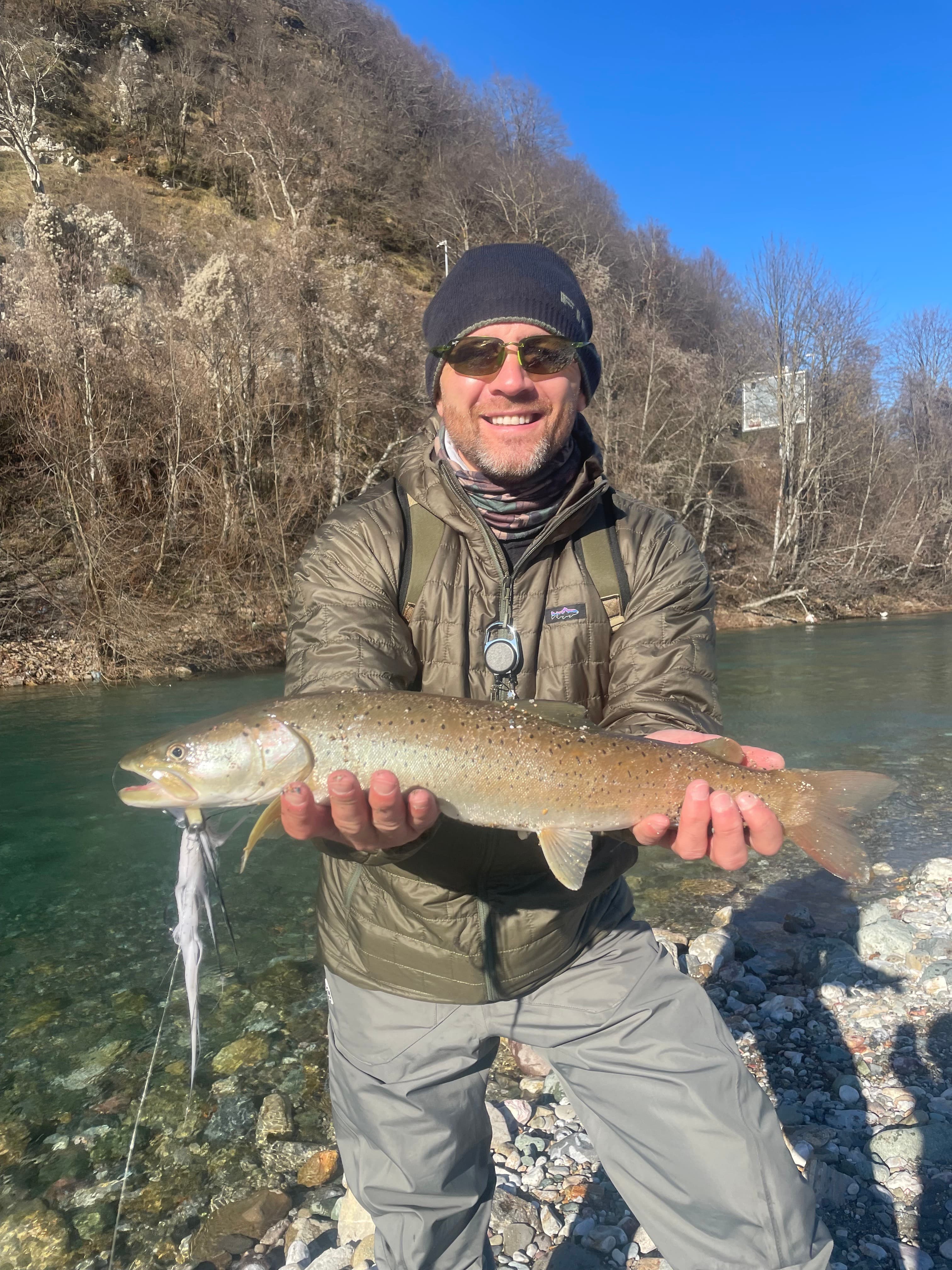An angler holding a huchen on the Savinja on a bright winter day